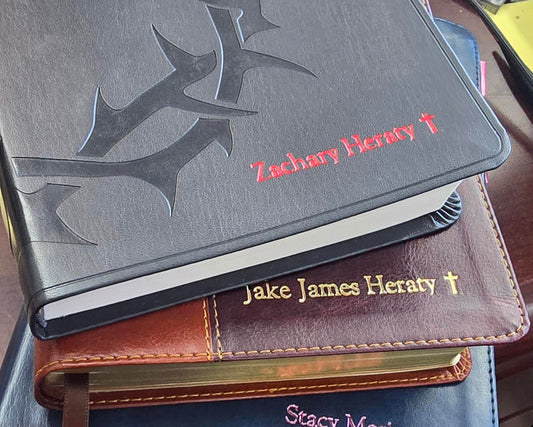 Stack of embossed leather bibles with personalized names and text.