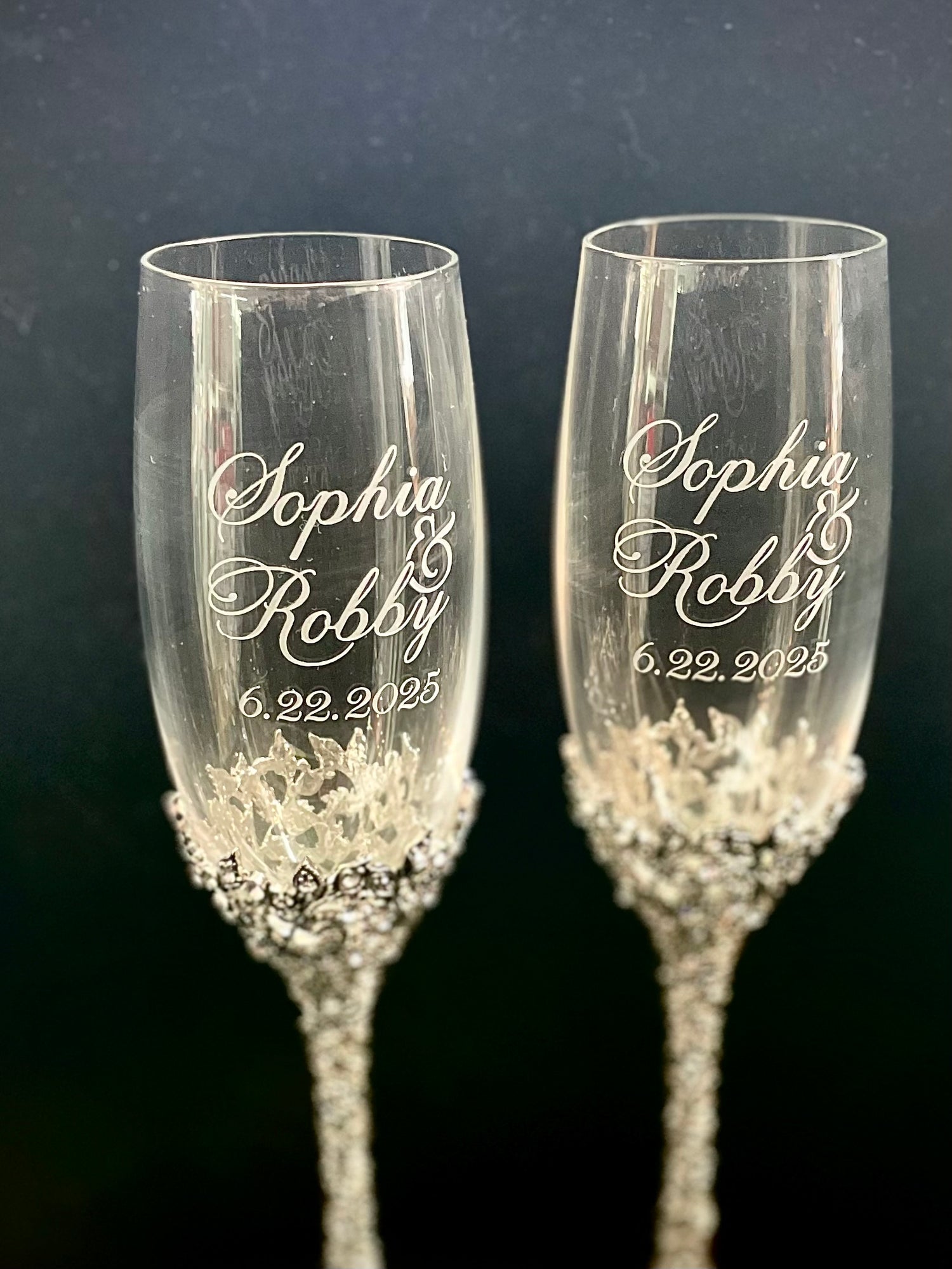Two champagne flutes with engraved names and date on a dark background